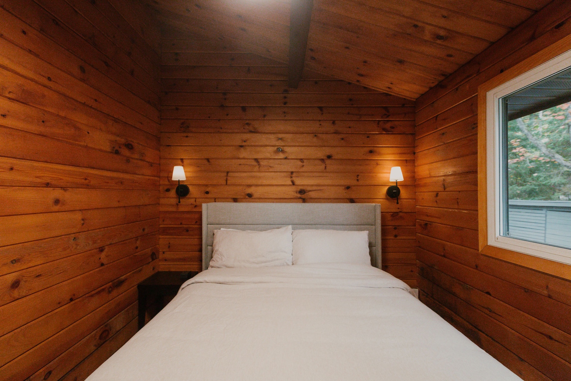 Cozy bedroom with wood walls and bedside sconces
